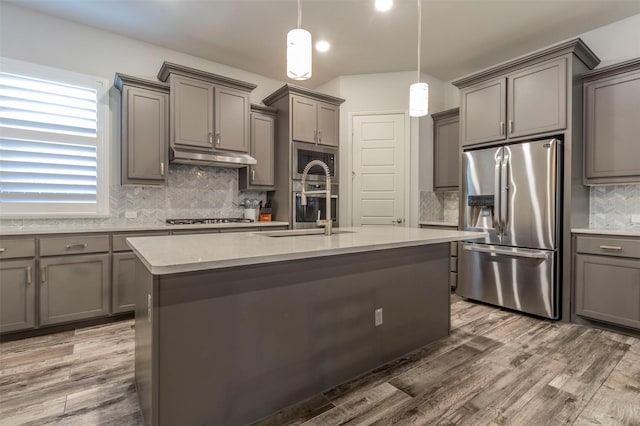 kitchen with pendant lighting, sink, gray cabinets, a kitchen island with sink, and stainless steel appliances