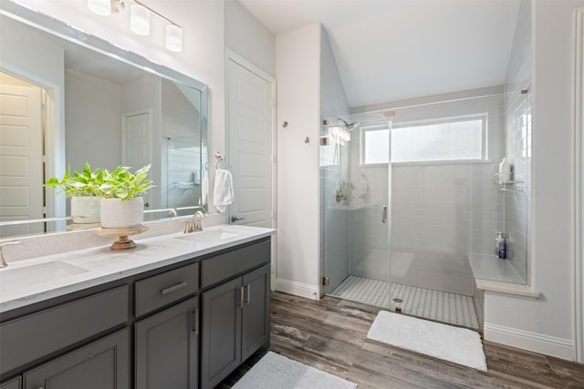 bathroom with vanity, hardwood / wood-style flooring, a shower with shower door, and vaulted ceiling