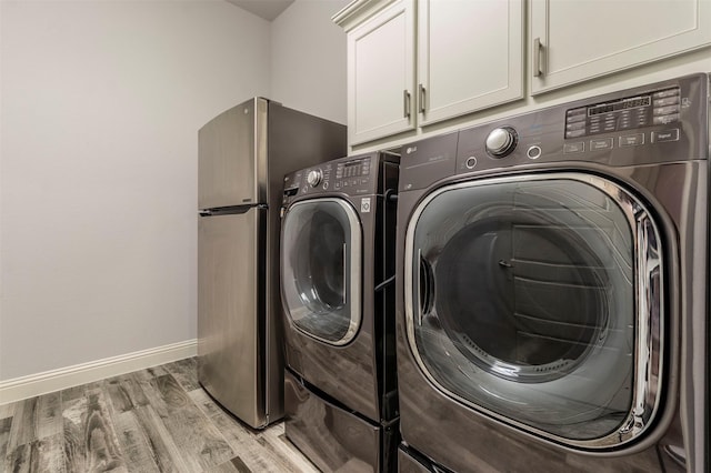 washroom featuring cabinets, light hardwood / wood-style floors, and washer and dryer