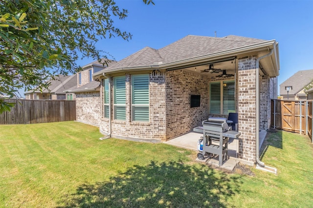 rear view of house with ceiling fan, a yard, and a patio