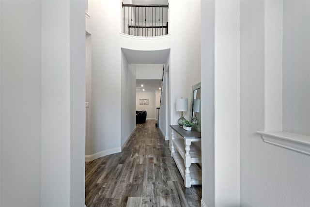 hallway featuring dark hardwood / wood-style flooring and a towering ceiling