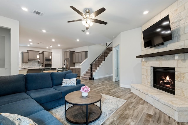 living room with ceiling fan, a fireplace, and light hardwood / wood-style floors