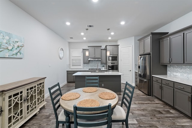 kitchen with gray cabinets, appliances with stainless steel finishes, dark hardwood / wood-style floors, wine cooler, and a center island with sink