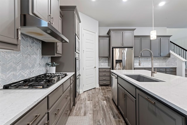 kitchen featuring pendant lighting, sink, gray cabinets, appliances with stainless steel finishes, and light stone countertops