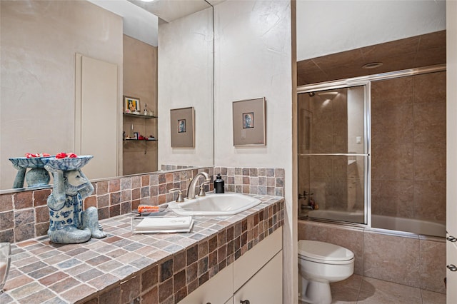 full bathroom featuring decorative backsplash, enclosed tub / shower combo, vanity, toilet, and tile patterned floors