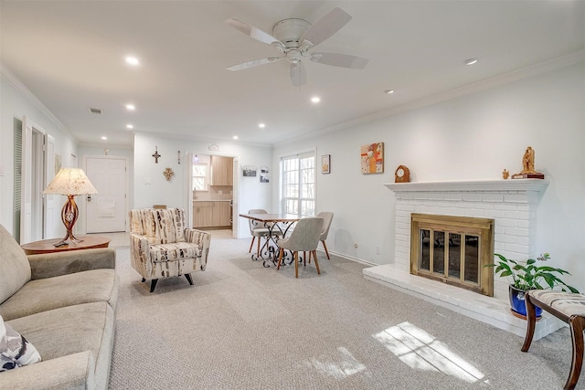 carpeted living room featuring a fireplace, ornamental molding, and ceiling fan