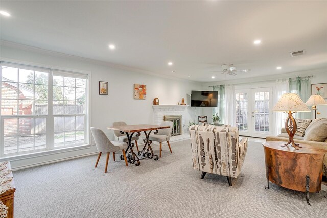 living room with light colored carpet, a fireplace, ornamental molding, and ceiling fan