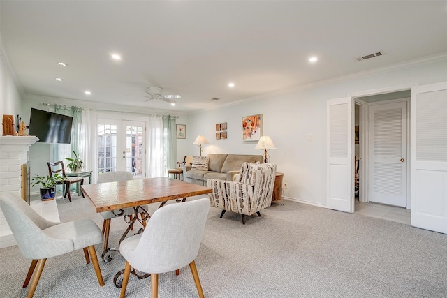 carpeted dining area with a fireplace, ornamental molding, french doors, and ceiling fan