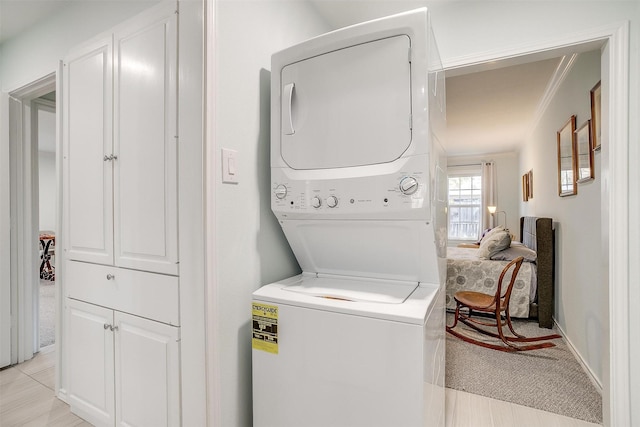 laundry area featuring crown molding and stacked washing maching and dryer