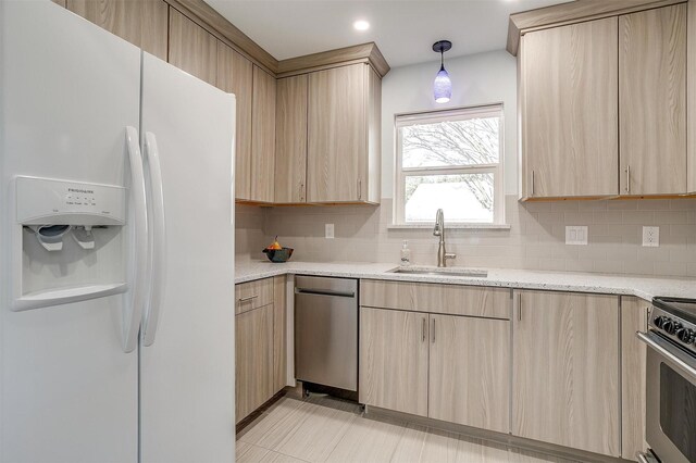 kitchen with light brown cabinetry, sink, hanging light fixtures, stainless steel appliances, and light stone countertops