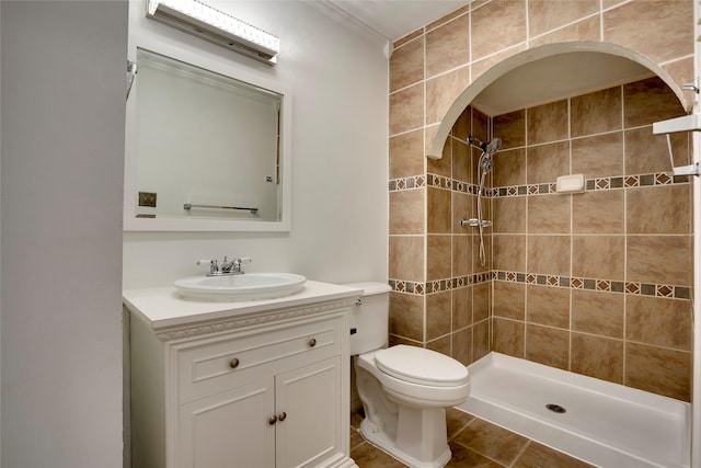 bathroom with vanity, tile patterned floors, toilet, and tiled shower