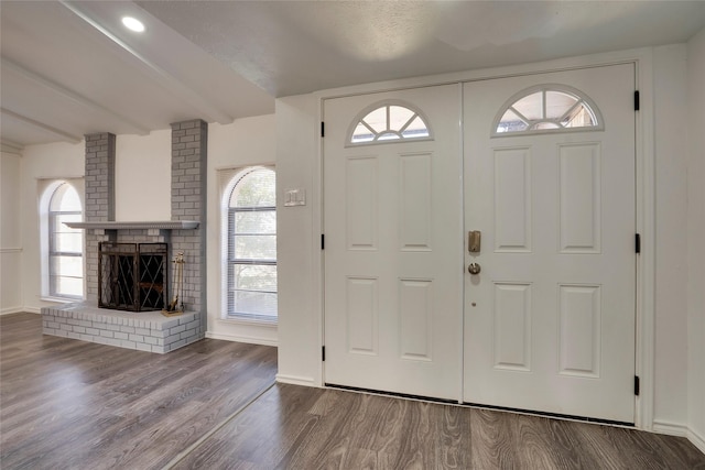 entryway with hardwood / wood-style floors, beam ceiling, a fireplace, and a healthy amount of sunlight