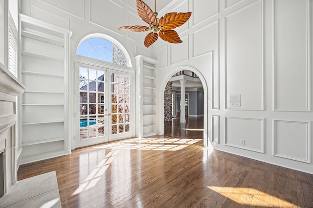 unfurnished living room featuring plenty of natural light, built in features, and wood-type flooring