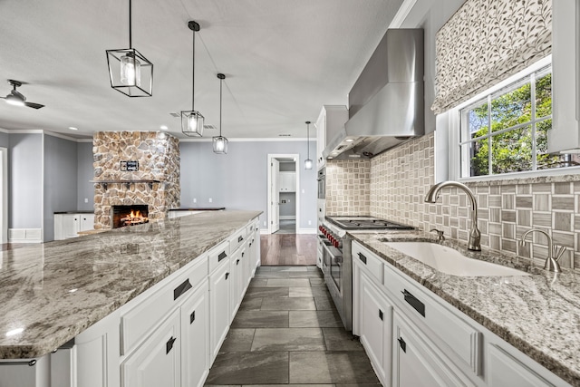 5008 Bellerive Dr, Dallas, TX 75287 - kitchen featuring wall chimney range hood, a sink, stainless steel stove, decorative backsplash, and a stone fireplace