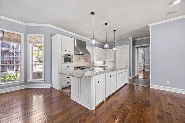 kitchen featuring wall chimney exhaust hood, white cabinetry, stainless steel oven, decorative light fixtures, and a center island