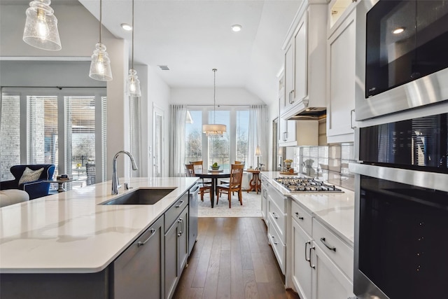 kitchen with white cabinetry, sink, decorative light fixtures, and a kitchen island with sink