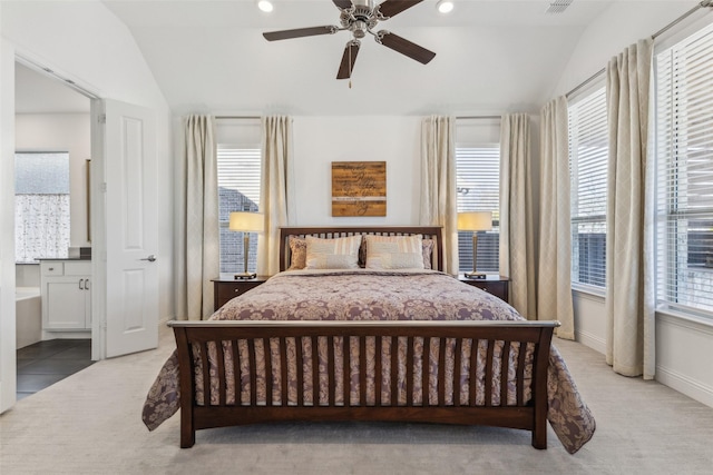 carpeted bedroom featuring multiple windows, vaulted ceiling, ceiling fan, and ensuite bathroom