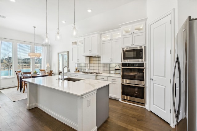 kitchen featuring sink, decorative light fixtures, appliances with stainless steel finishes, an island with sink, and white cabinets