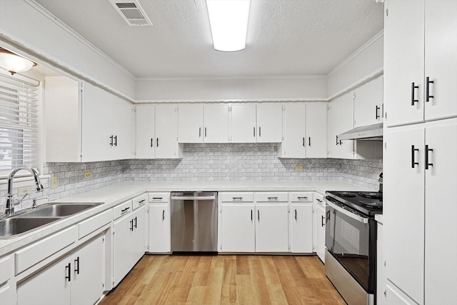 kitchen featuring tasteful backsplash, sink, white cabinets, light hardwood / wood-style floors, and stainless steel appliances