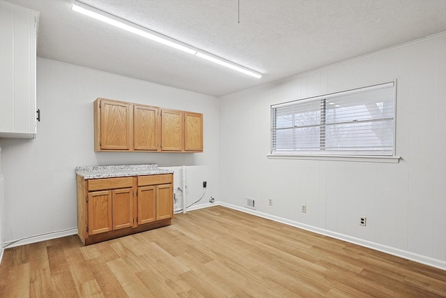 washroom with cabinets, washer hookup, a textured ceiling, and light hardwood / wood-style flooring