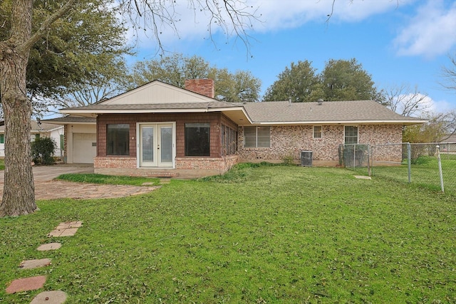 rear view of house featuring a garage, a lawn, french doors, and central air condition unit