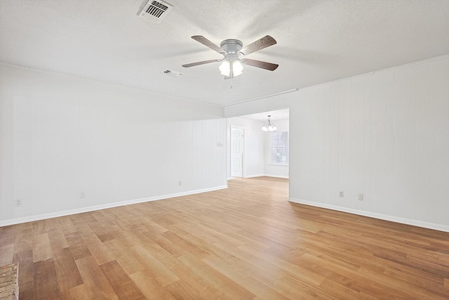 empty room with ceiling fan with notable chandelier, light hardwood / wood-style floors, and a textured ceiling