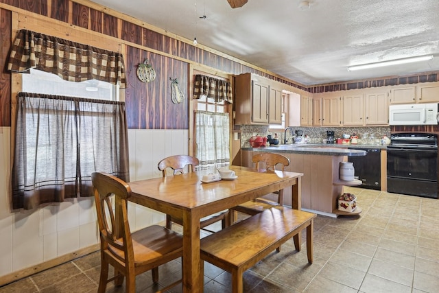 kitchen with light tile patterned floors, decorative backsplash, and black appliances