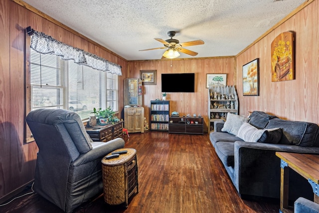 living room with dark wood-type flooring, wooden walls, a textured ceiling, and ceiling fan