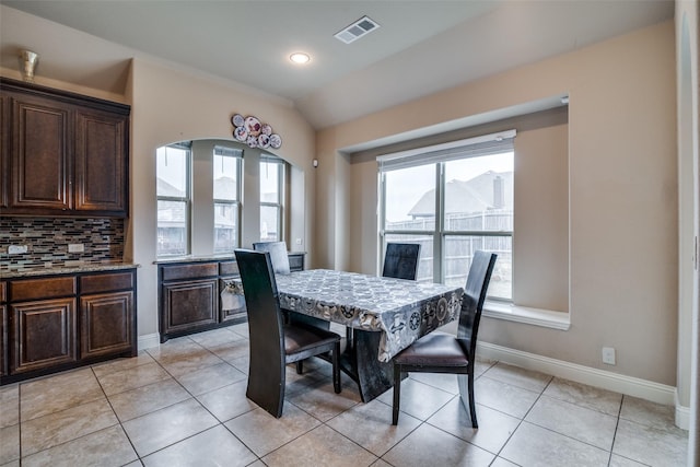 tiled dining room featuring plenty of natural light and lofted ceiling