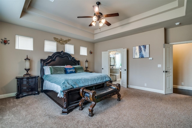 carpeted bedroom featuring connected bathroom, a raised ceiling, and ceiling fan