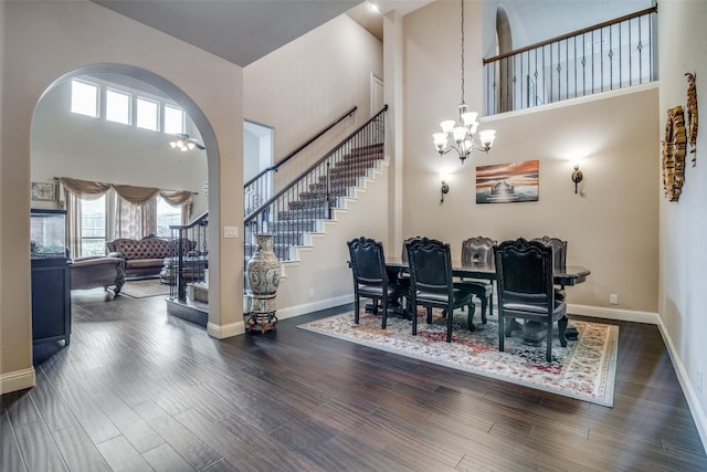 dining space with dark hardwood / wood-style flooring, a towering ceiling, and a chandelier