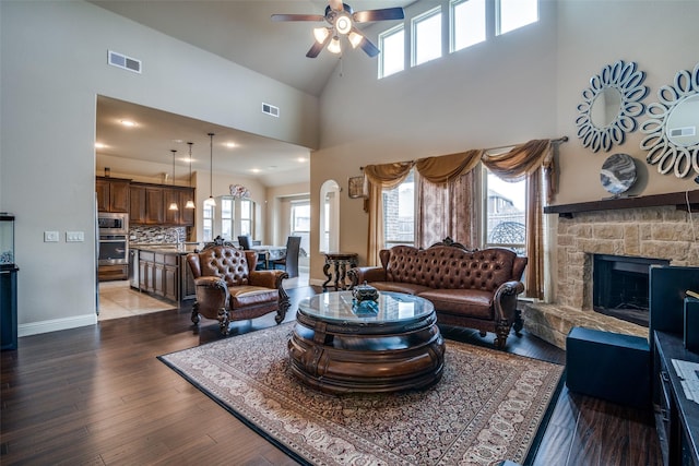 living room featuring a fireplace, dark hardwood / wood-style floors, ceiling fan, and a high ceiling