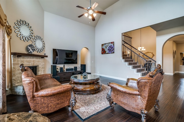 living room with dark hardwood / wood-style flooring, a stone fireplace, and high vaulted ceiling