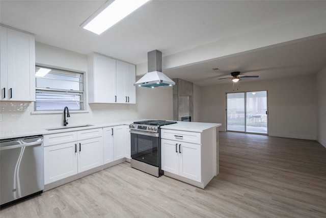 kitchen featuring sink, white cabinetry, island range hood, stainless steel appliances, and light hardwood / wood-style floors