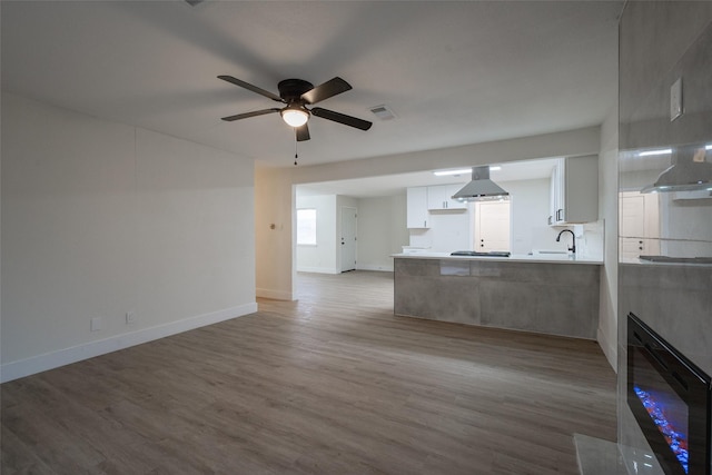 unfurnished living room with sink, hardwood / wood-style flooring, and ceiling fan