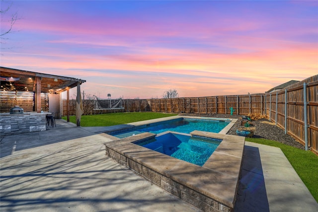 pool at dusk with an in ground hot tub, a yard, a trampoline, and a patio area