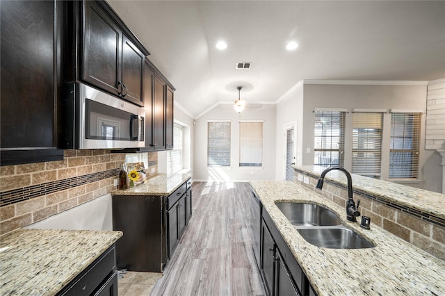 kitchen featuring sink, light stone counters, light hardwood / wood-style flooring, ornamental molding, and backsplash