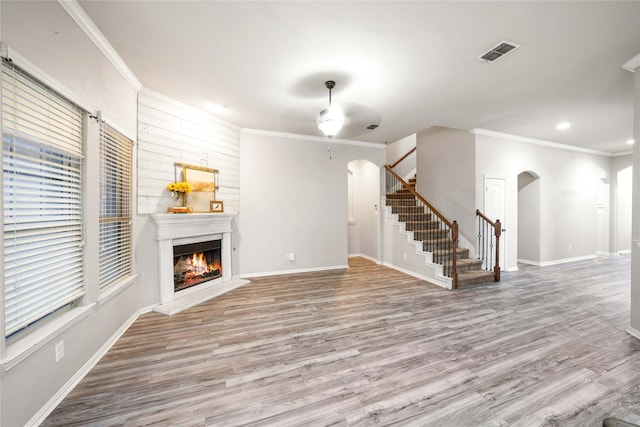 unfurnished living room with ceiling fan, ornamental molding, and light hardwood / wood-style floors