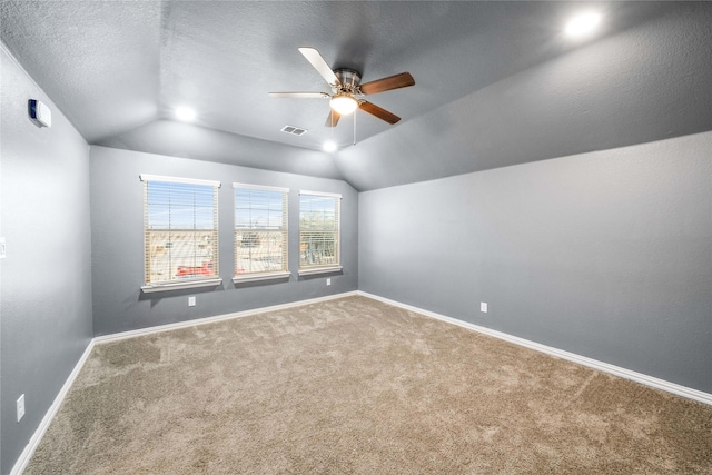 interior space with vaulted ceiling, ceiling fan, carpet floors, and a textured ceiling