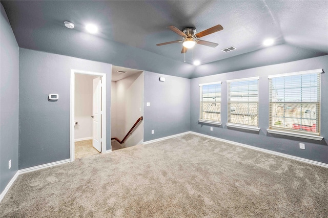 carpeted spare room with ceiling fan, vaulted ceiling, and a textured ceiling