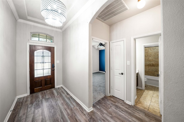 foyer featuring hardwood / wood-style floors, crown molding, and a chandelier