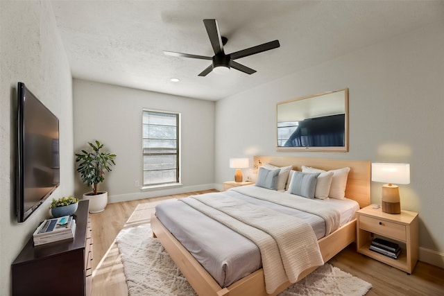 bedroom with a textured ceiling, light hardwood / wood-style floors, and ceiling fan