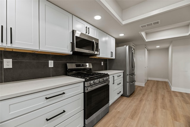 kitchen with stainless steel appliances, light hardwood / wood-style flooring, white cabinets, and decorative backsplash