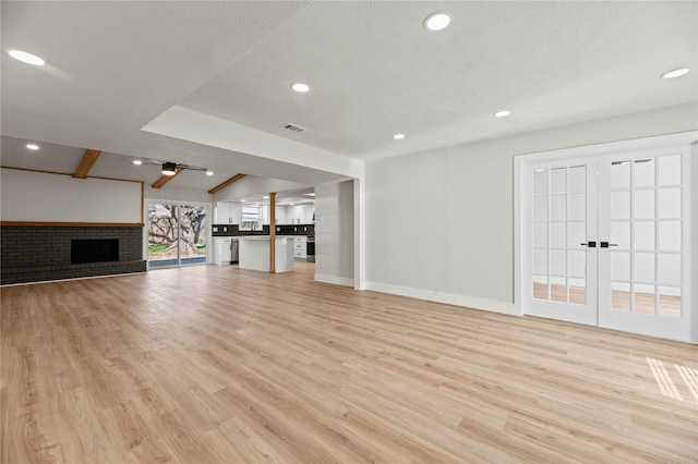 unfurnished living room featuring ceiling fan, a fireplace, a textured ceiling, and light wood-type flooring