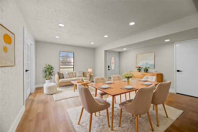 dining room with light hardwood / wood-style floors and a textured ceiling