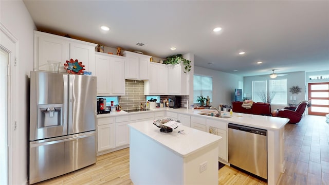 kitchen with sink, white cabinetry, light hardwood / wood-style flooring, appliances with stainless steel finishes, and kitchen peninsula