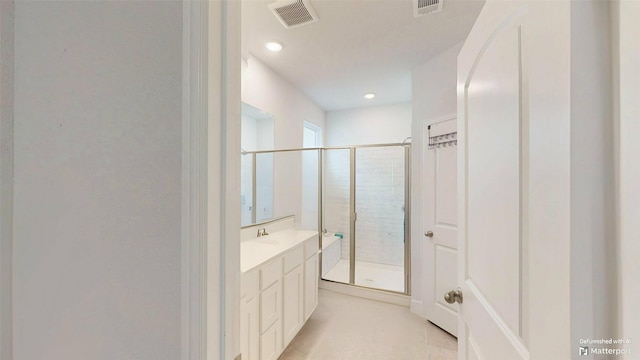 bathroom featuring a shower with door and vanity