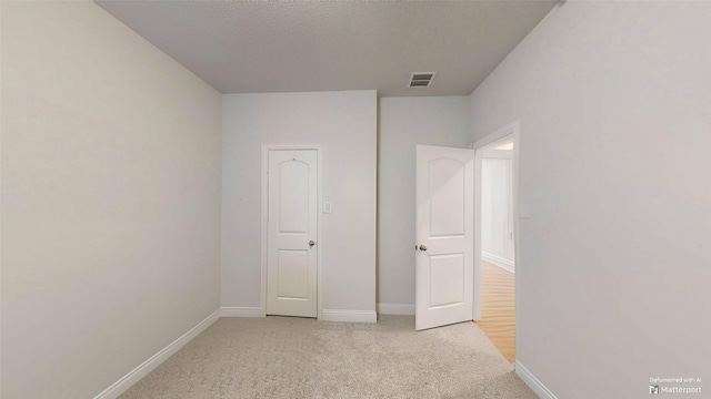 unfurnished bedroom with light colored carpet and a textured ceiling