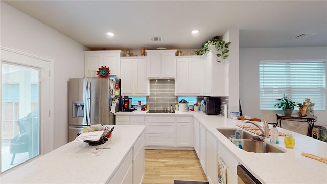 kitchen with stainless steel fridge, sink, and white cabinets