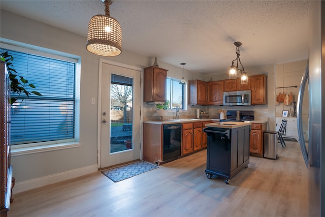 kitchen with sink, hanging light fixtures, light wood-type flooring, appliances with stainless steel finishes, and a kitchen island